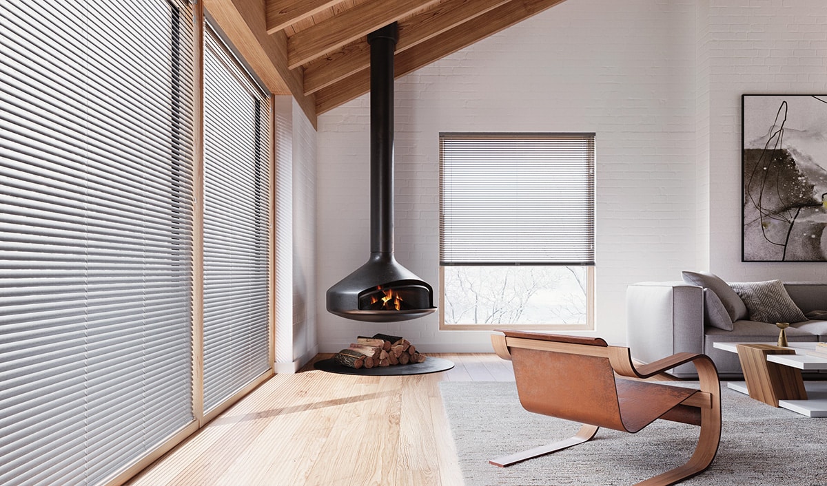 Aluminum blinds filtering in natural light into a cabin looking living room.