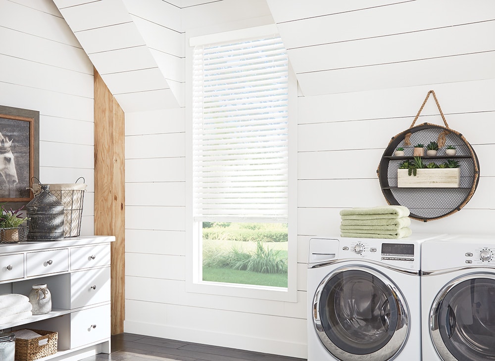 Faux Wood Blinds filtering in sunlight in a farmhouse styled laundry room. 