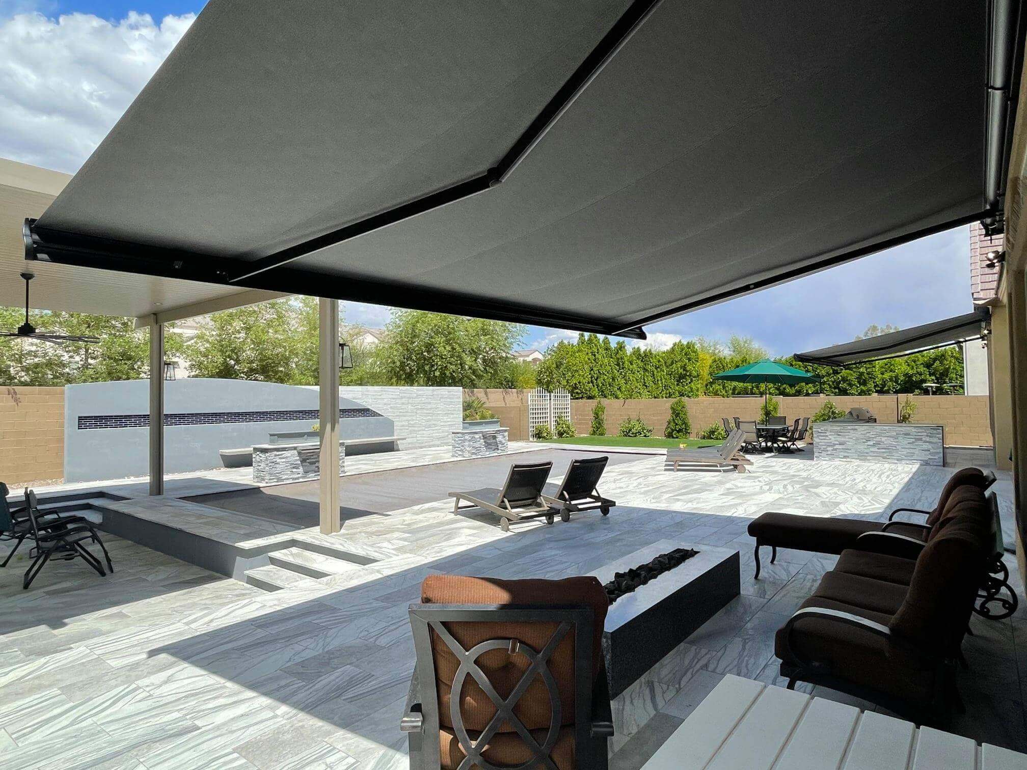 A large awning fully extended over a peaceful outdoor seating area in a spacious backyard.